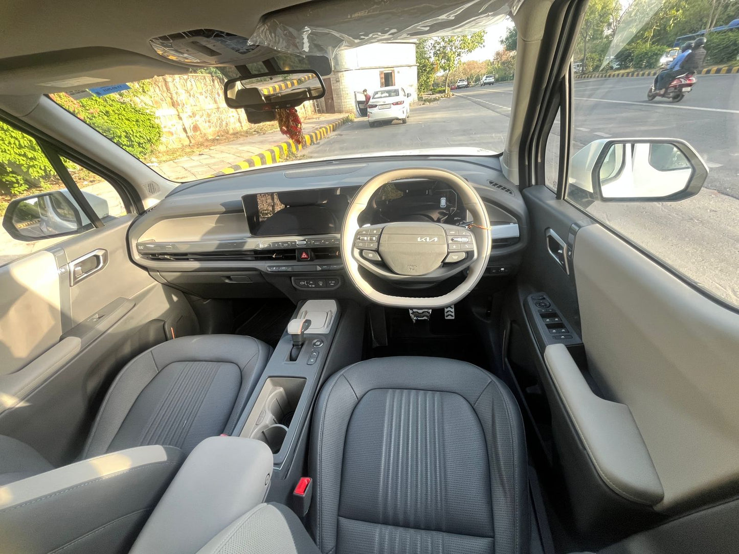 Car interior with dashboard and steering wheel, showing a road outside.