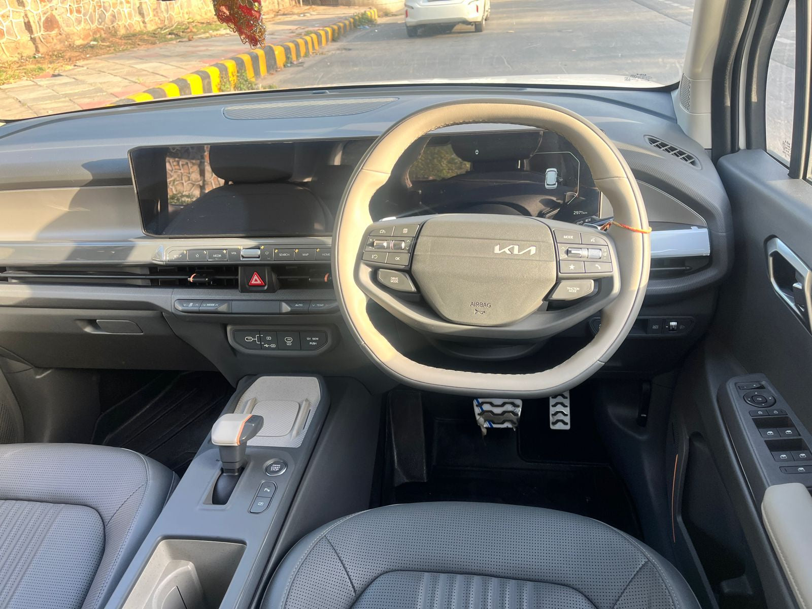 Car interior with steering wheel and dashboard, showing Kia logo.