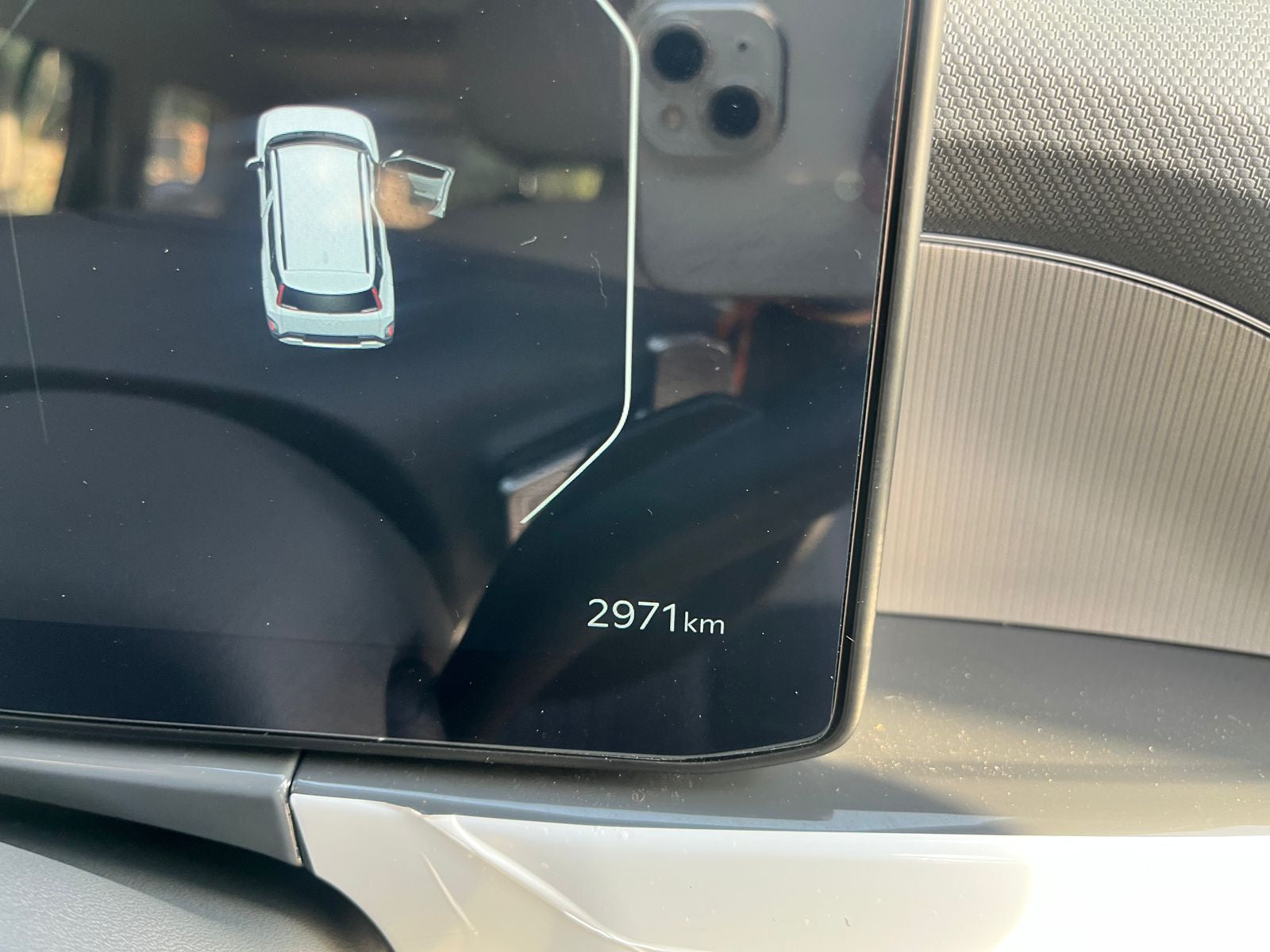 Car dashboard with digital display showing 2971 km and a small icon on the left.