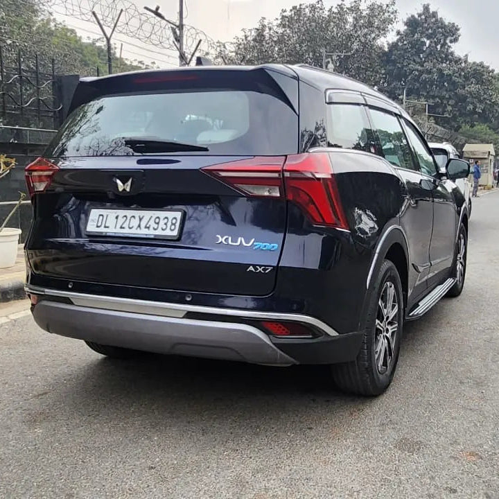 Black SUV on a road with trees and buildings in the background