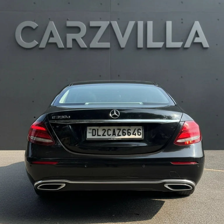 Black Mercedes-Benz car parked in front of a gray wall with 'CARZVILLA' branding.