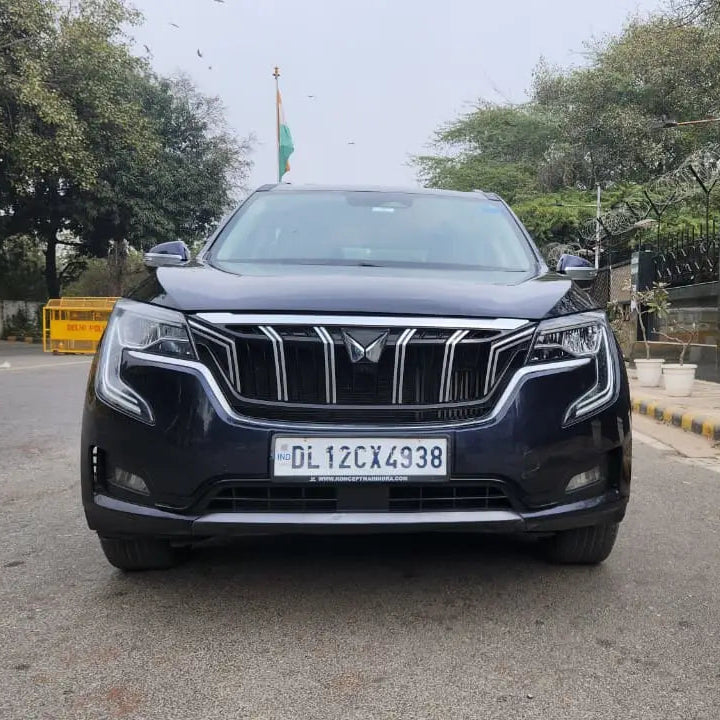 Black SUV on a road with trees and a building in the background