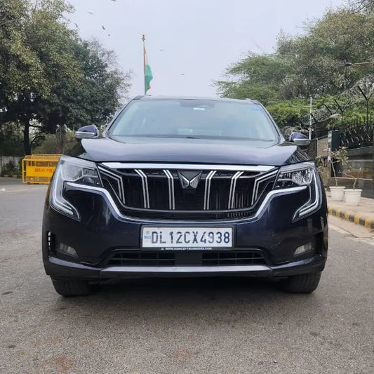 Black SUV on a road with trees and a building in the background