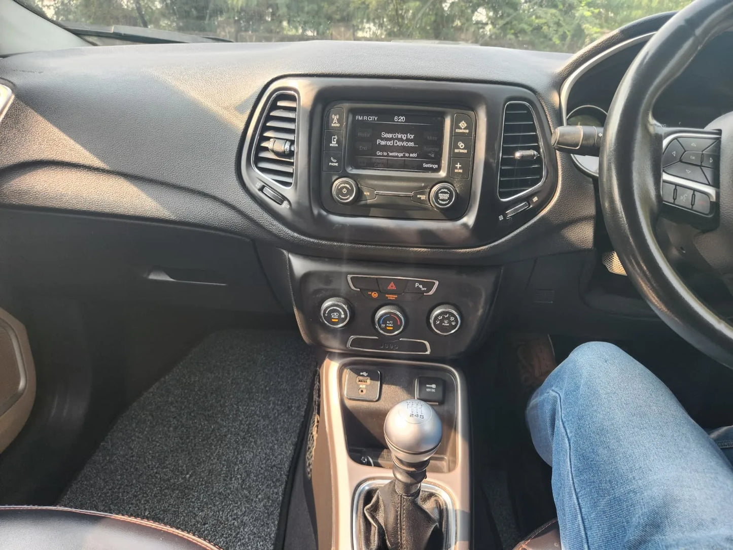 Car interior with dashboard, steering wheel, and gear shift.