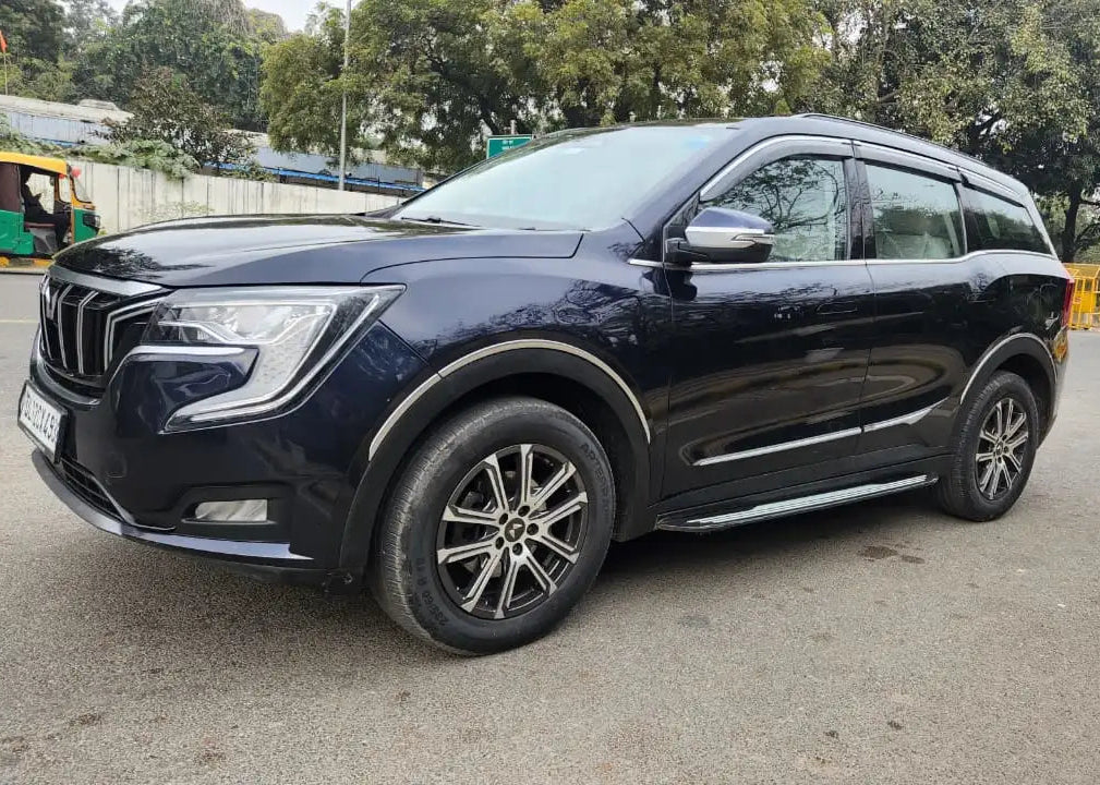 Black SUV parked on a road with trees in the background