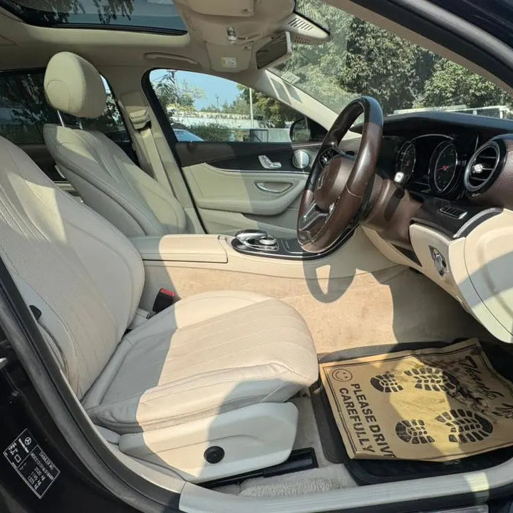 Car interior with beige seats and dashboard, showing a box on the floor.