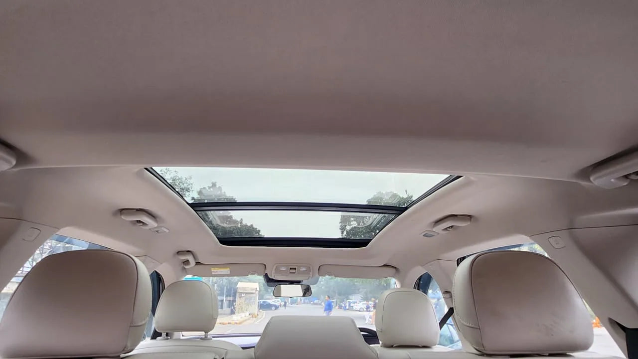 Car interior with a sunroof and beige seats.