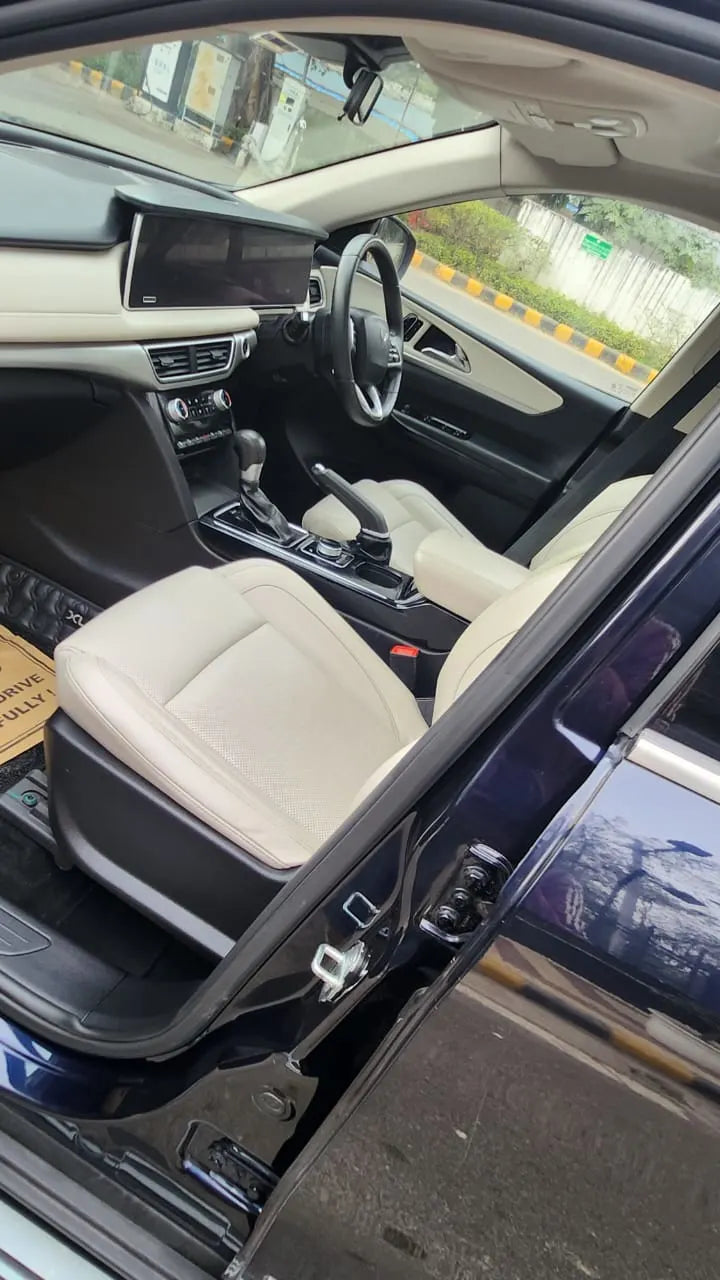 Car interior with beige seats and dashboard, showing a clear view of the steering wheel and gear shift.