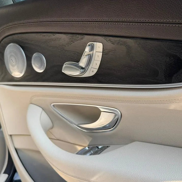 Close-up of a car door panel with chrome door handle and window controls.