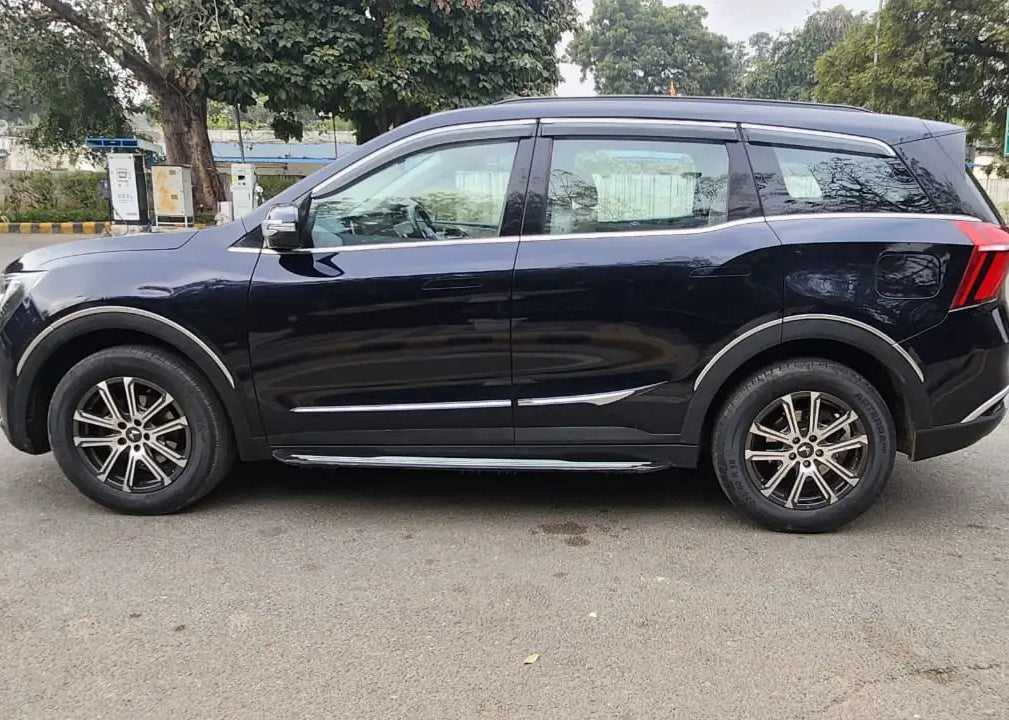 Black SUV parked on a road with trees and signs in the background