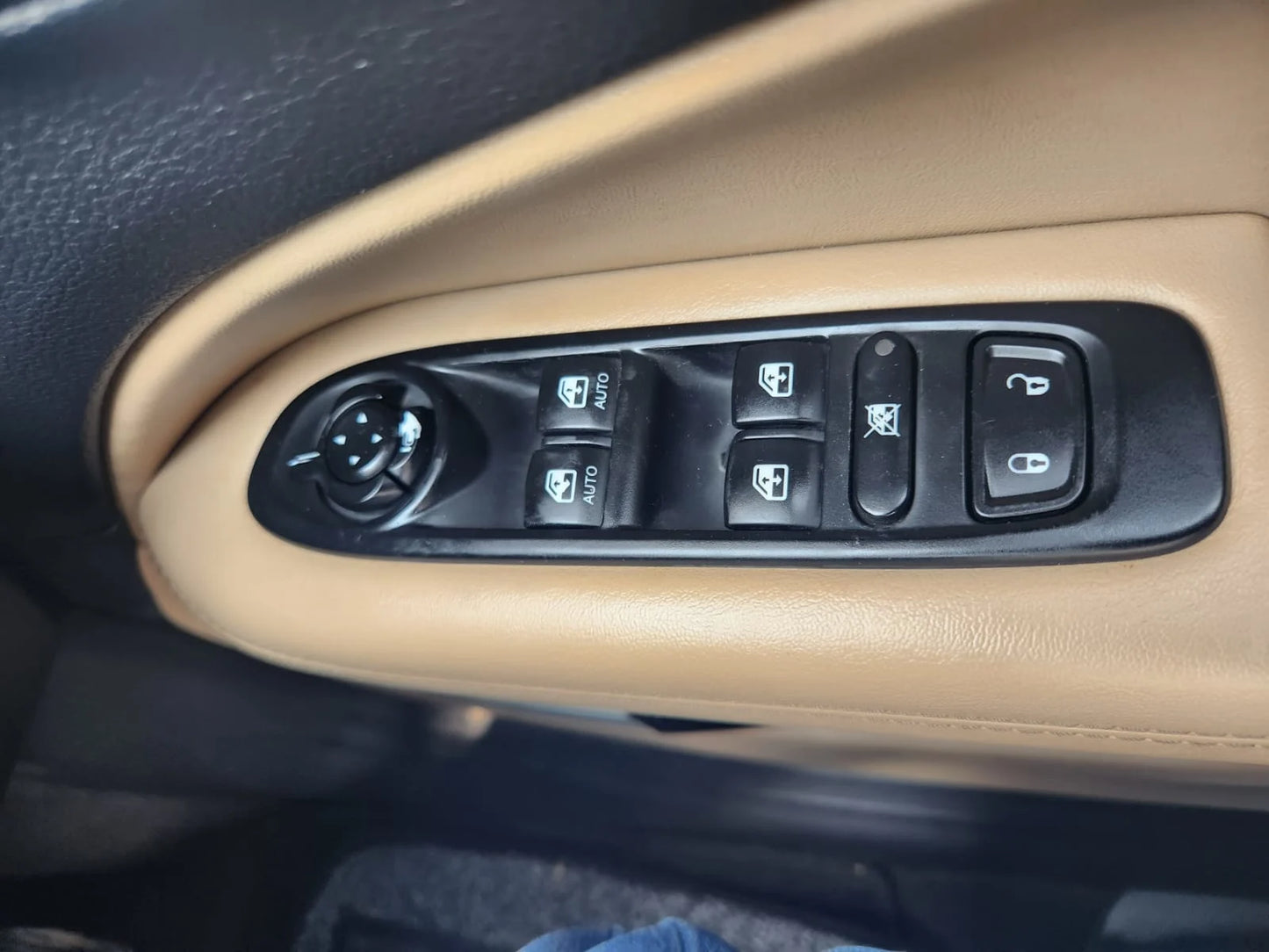 Car window control switch panel on a beige dashboard