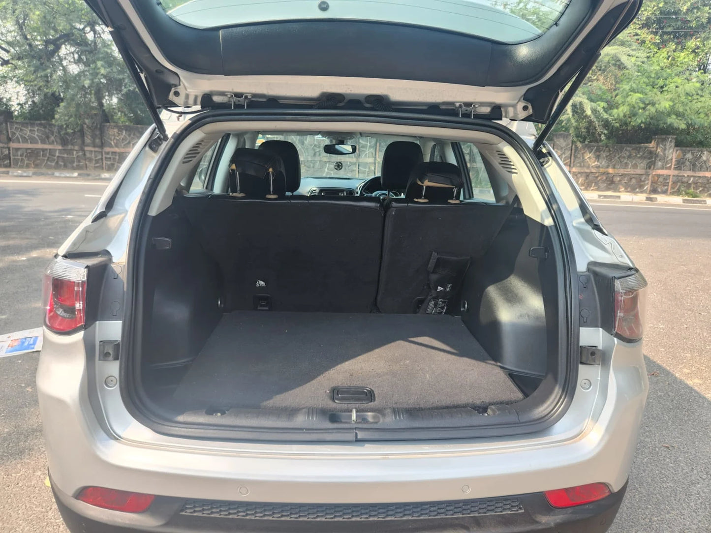 Car trunk with open lid on a road with trees in the background
